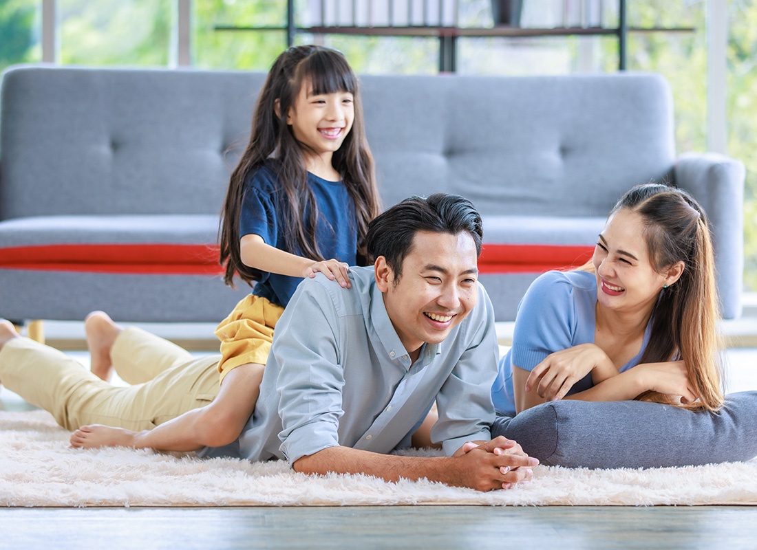 Personal Insurance - Happy Mother and Father Lay on Carpet While Daughter Sits on Father's Back at Home